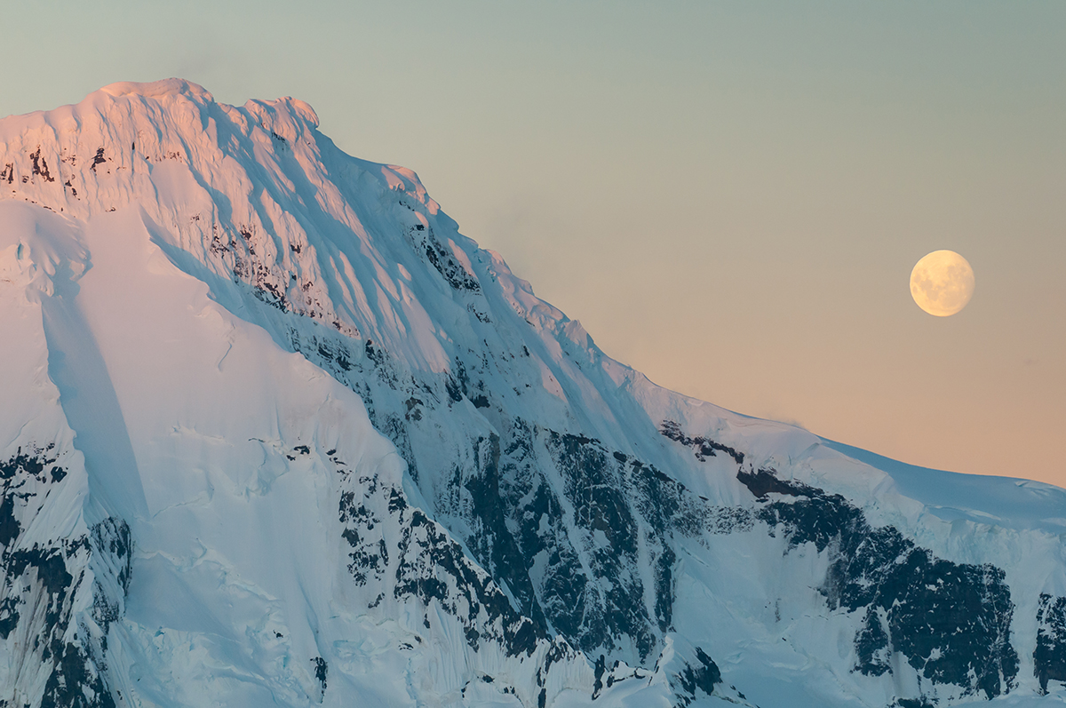 moonrise over a snow-capped mountain