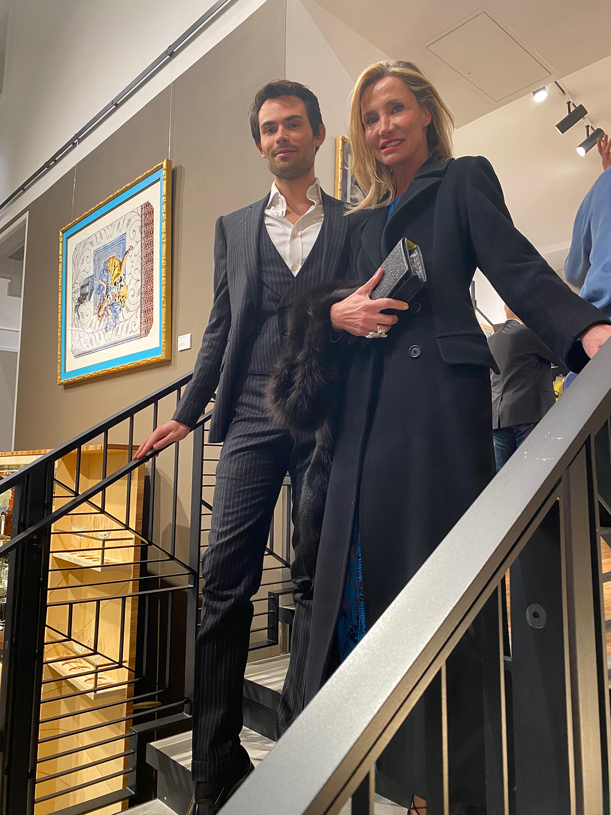 A man in a suit and a woman in a bleu dress standing on steps