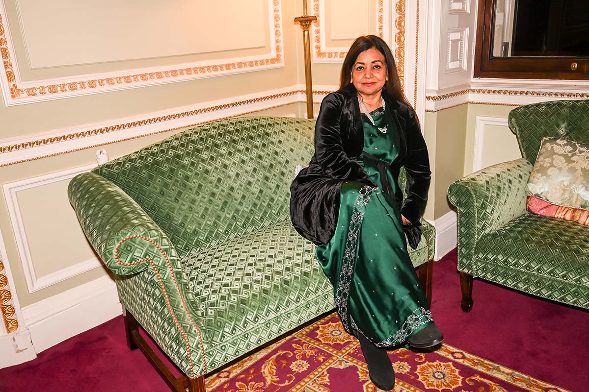 Surina Narula sitting on a green couch in a green dress