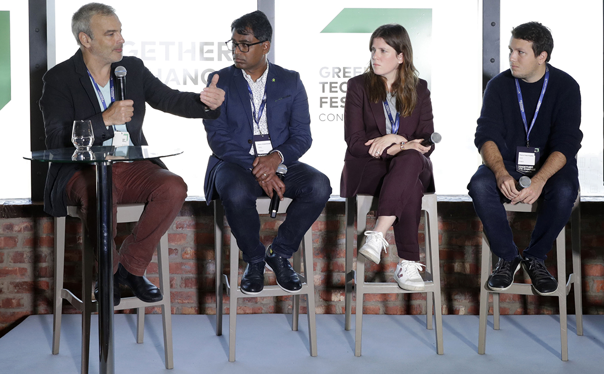 three men and a woman sitting on bar stools giving a panel discussion