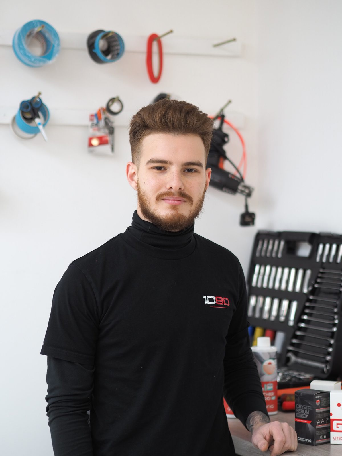 A man in a black uniform working in a car paint shop