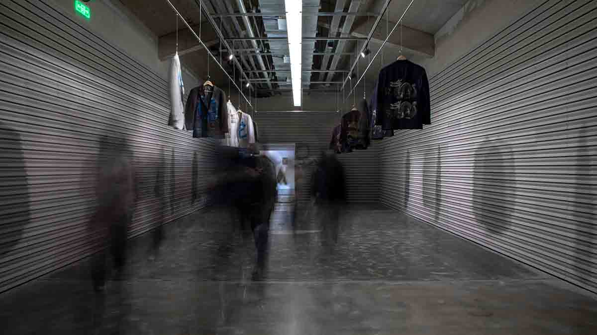 Blurry image of people walking through a grey tunnel like room