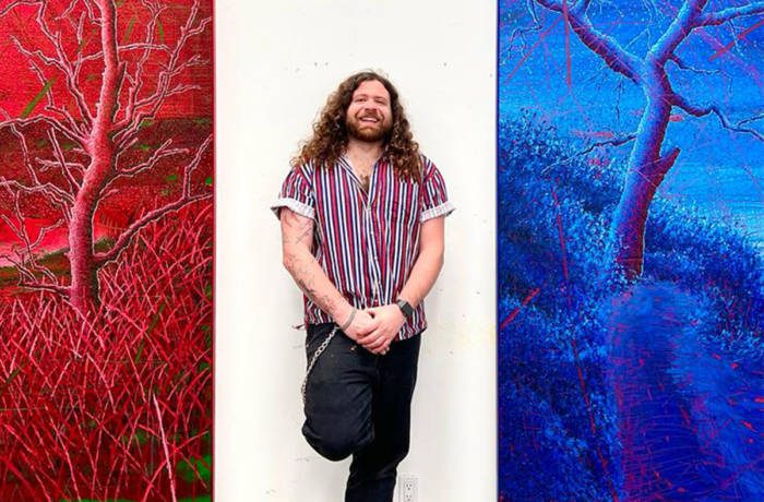 artist standing between a blue and red painting