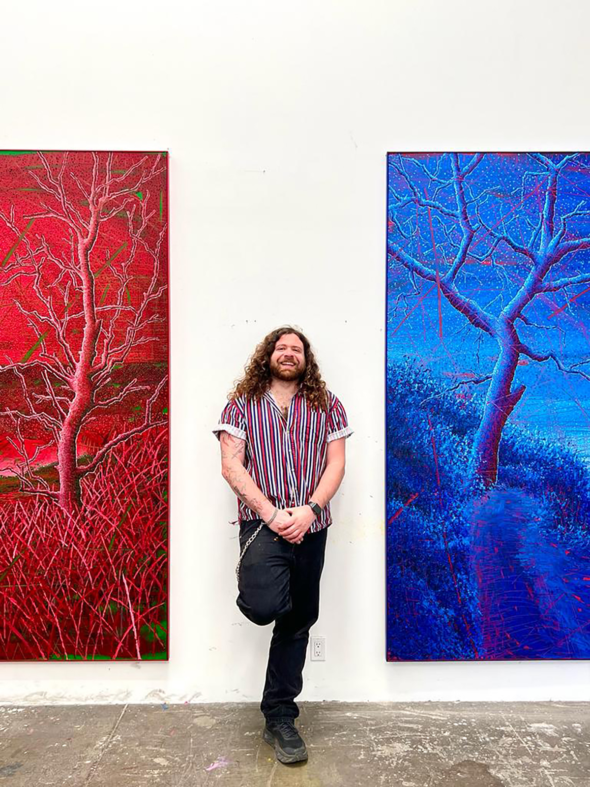 artist standing between a blue and red painting
