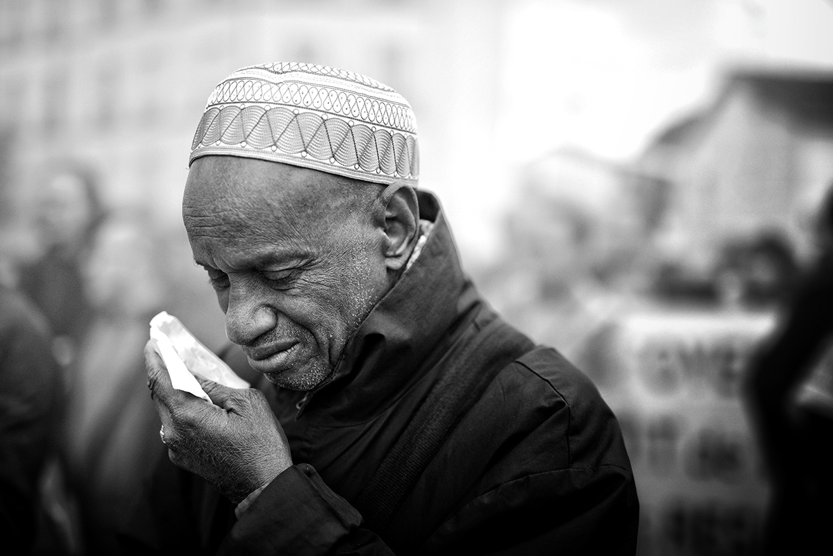 A man wearing a hat crying into a handkerchief