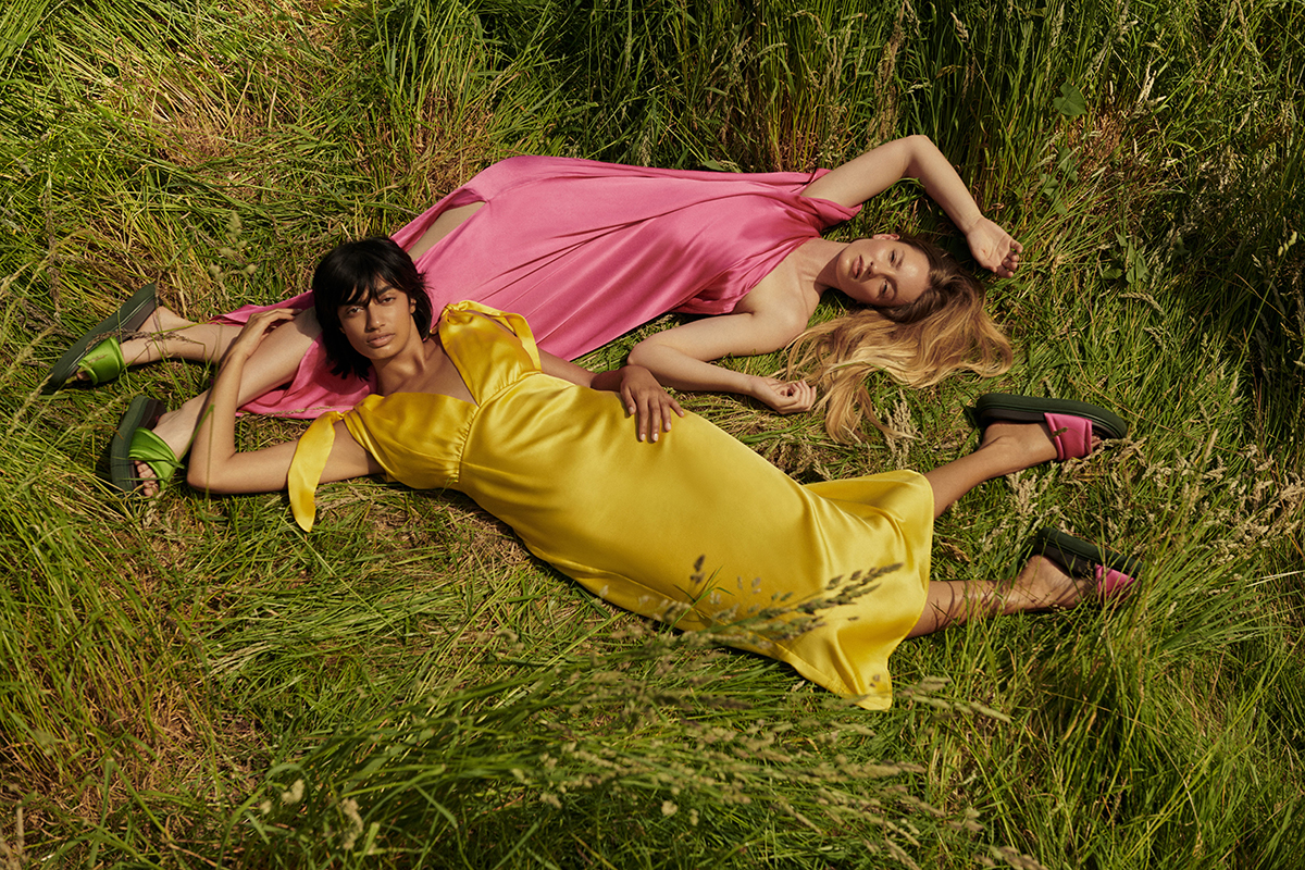 two girls in yellow and pink dresses lying on the grass