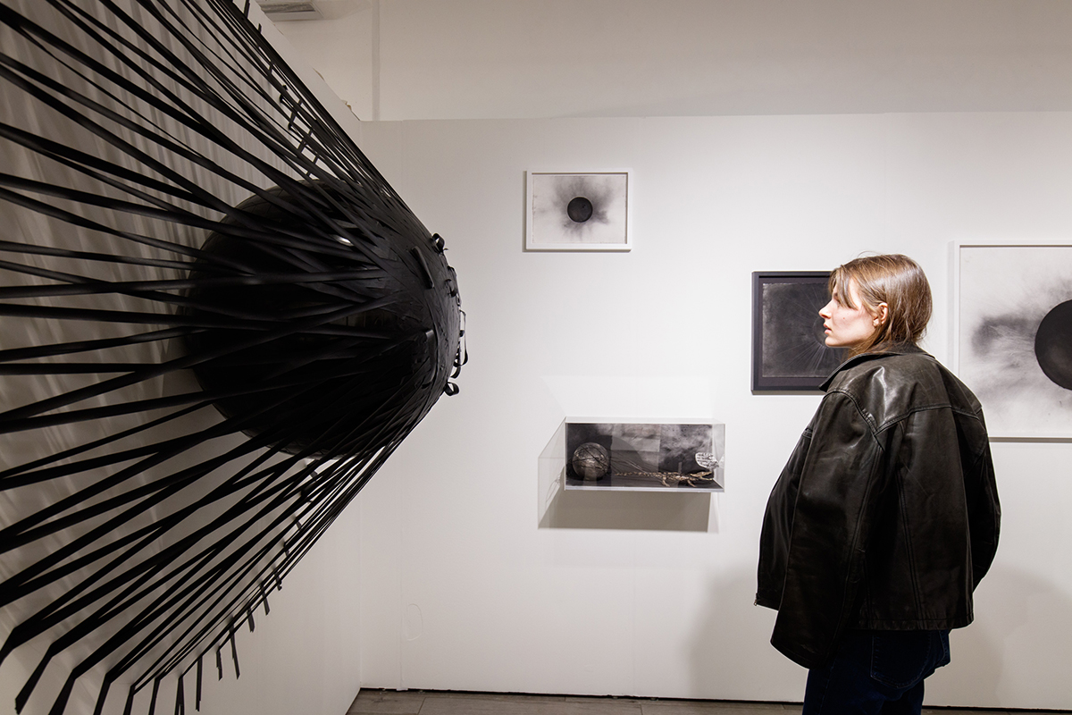 A woman staring at a black piece of art of coming out of the wall