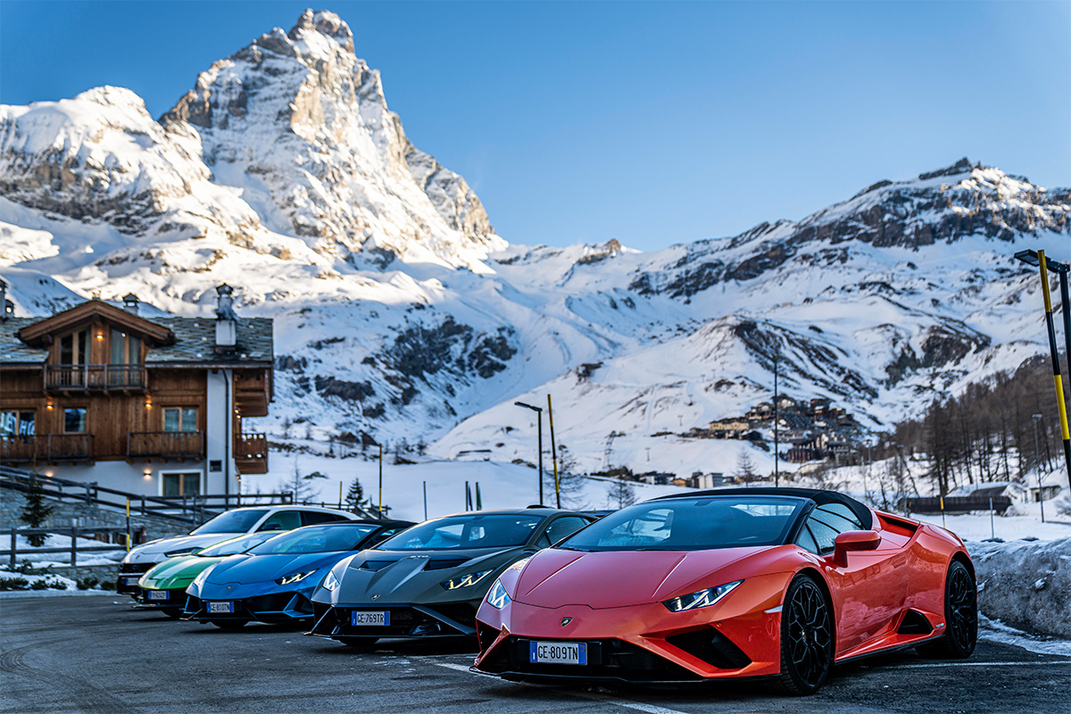 red, green and black lamborghinis parked in front of a mountain