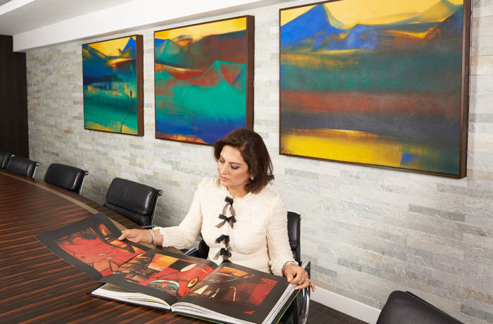 A woman in a white blazer reading an art book at a table