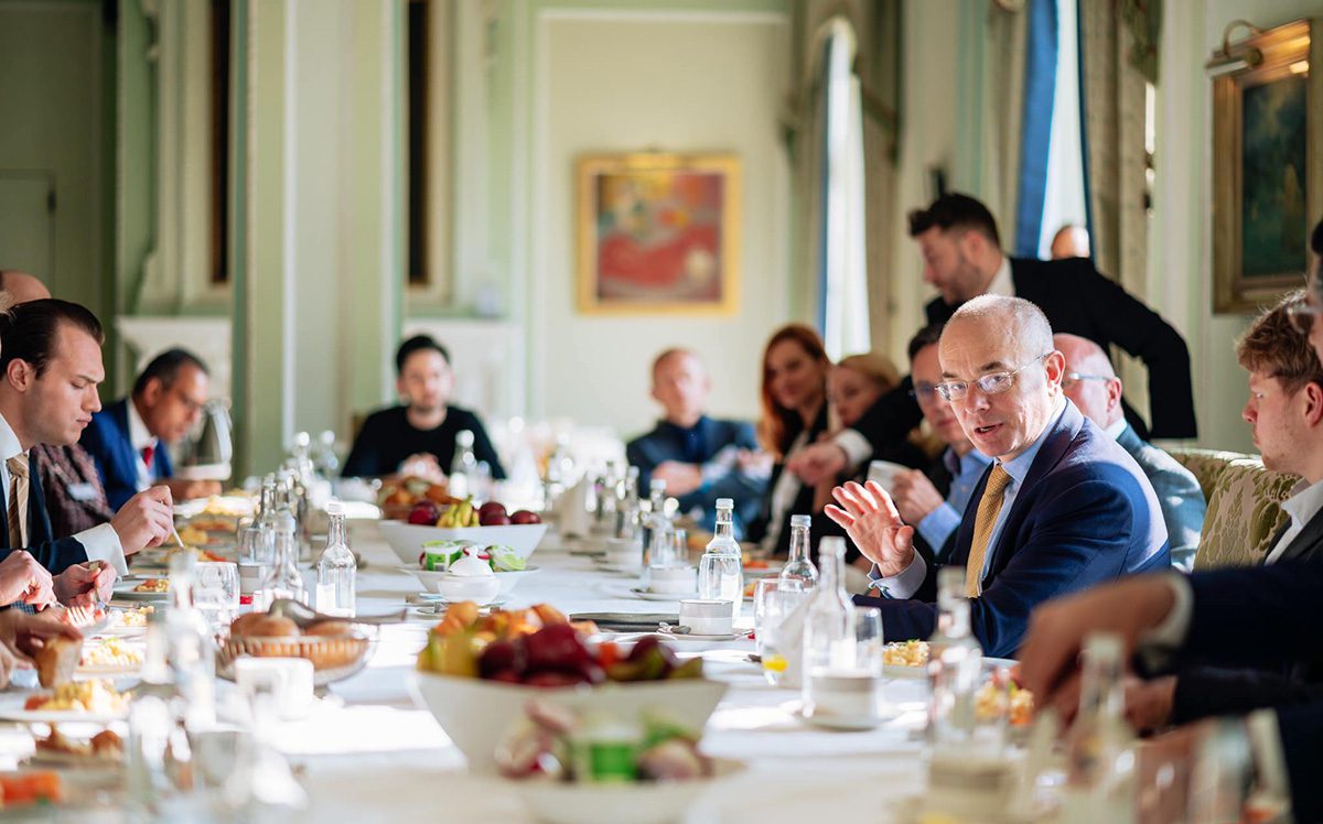 People sitting around a long table with breakfast food on it