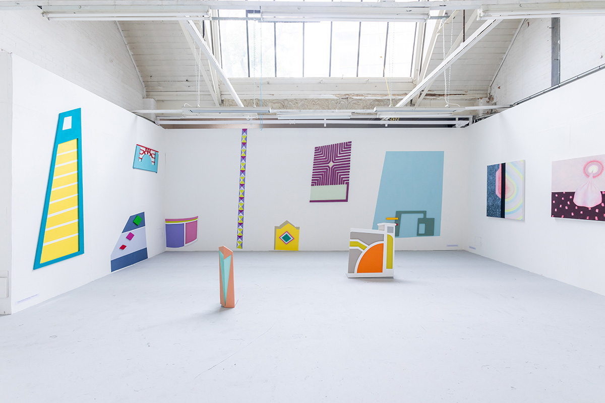 colourful art and installations in a plain white room with a window on the ceiling