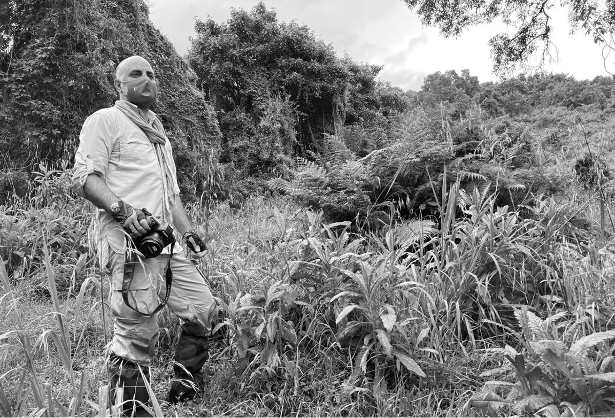 a man standing with a camera in a safari wearing a mask