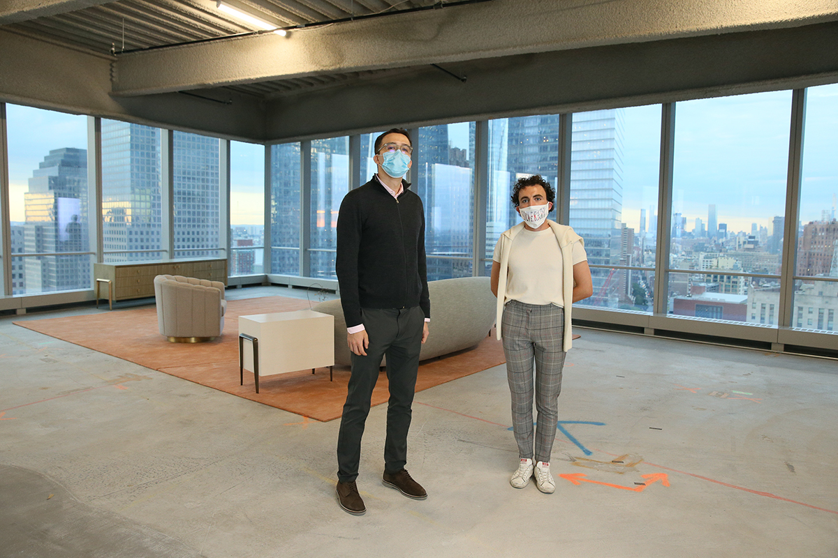 Two men standing with masks on in a lounge in a skyscraper