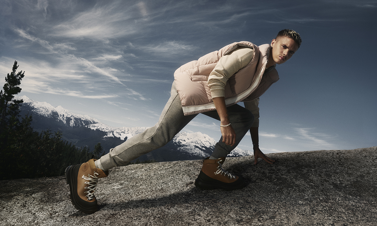 Romeo Beckham in a pink gilet, beige trousers and white boots crawling