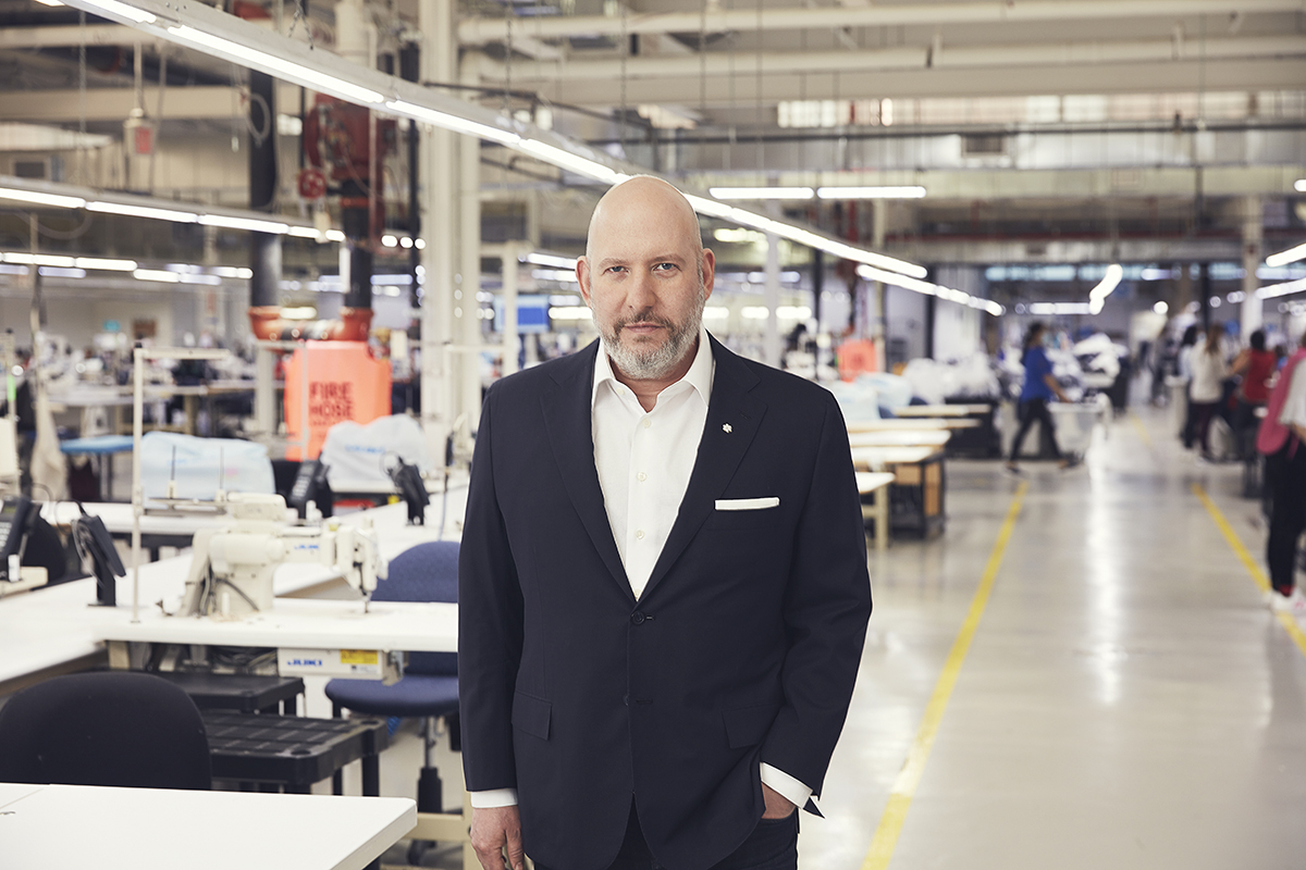 A bald man in a suit standing in a factory
