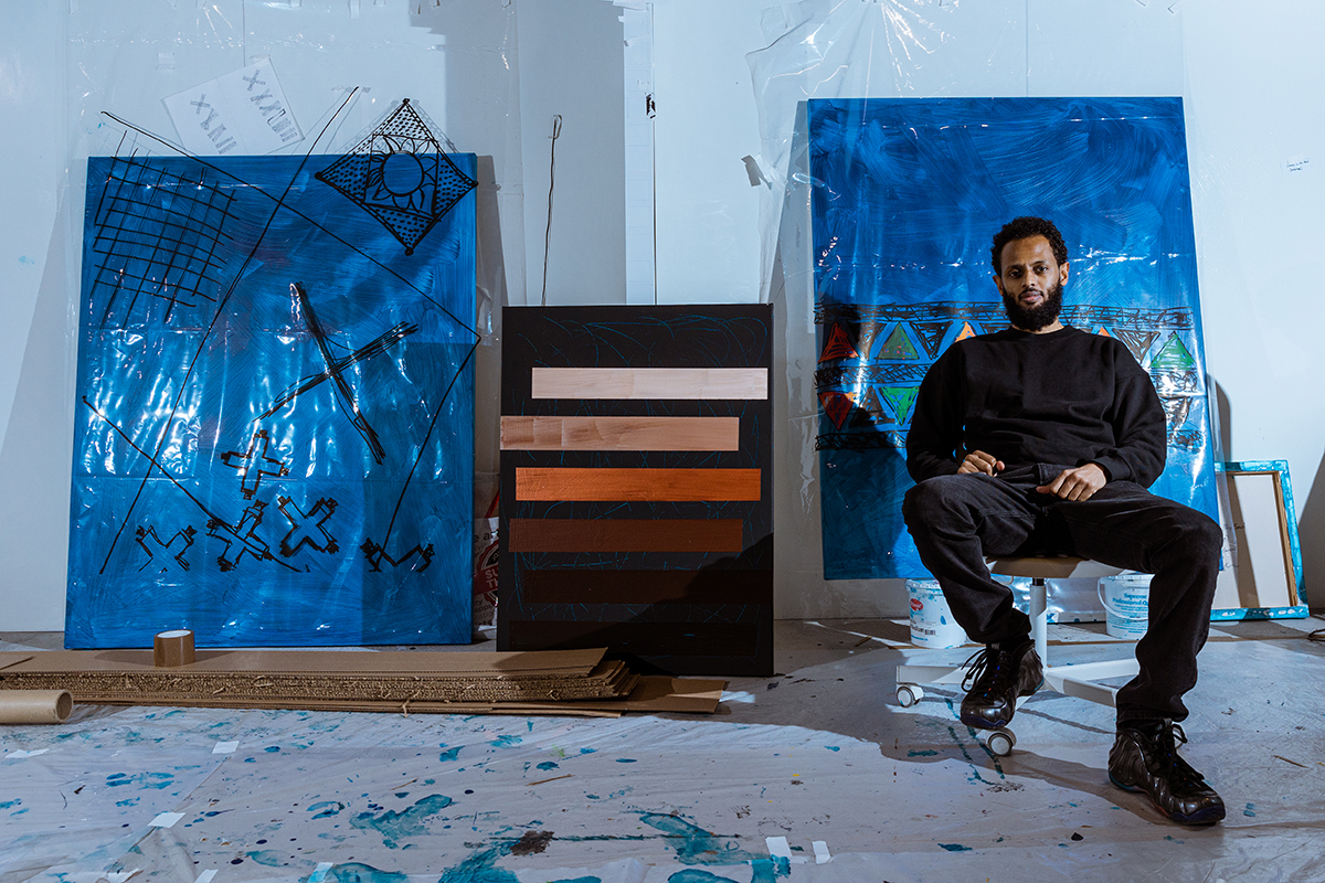 A man sitting in front of blue canvases
