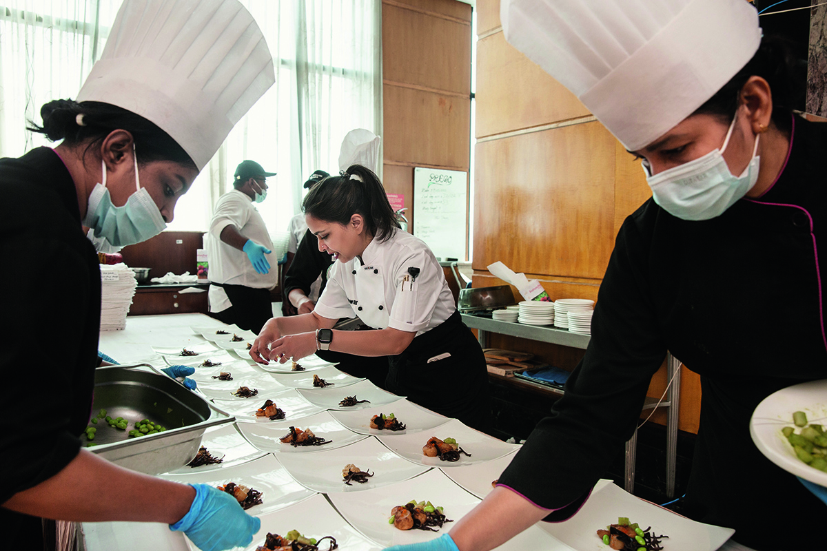 chefs working in a kitchen placing food on a plate