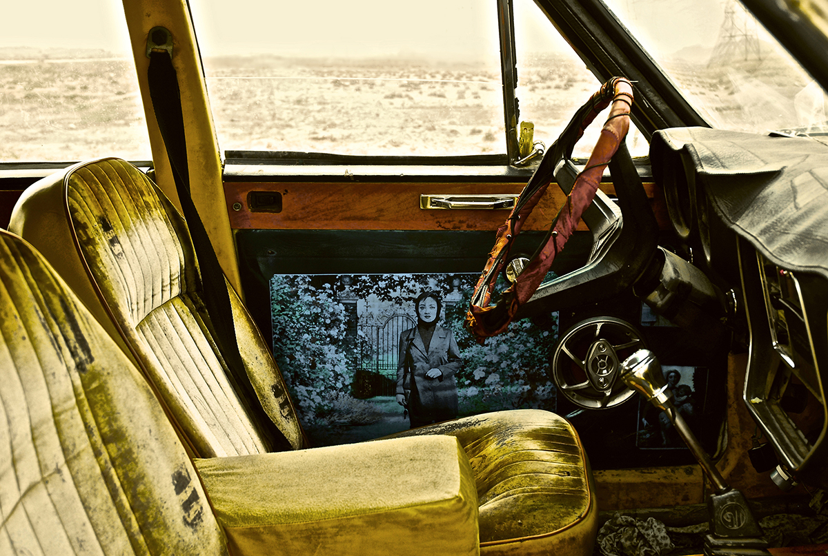 yellow car seats behind a wooden steering wheel and a blue painting