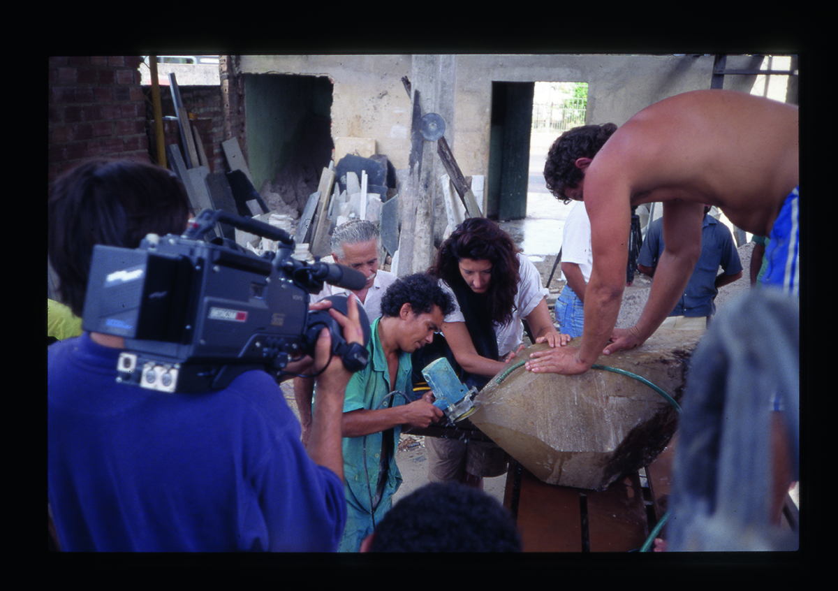 A group of people surrounding a rock being videoed