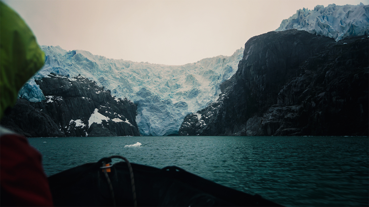 a boat in the sea in front of a snowy mountain