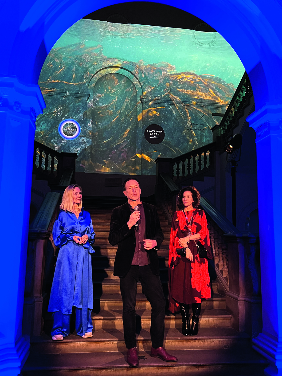 A man giving a speech in front of a staircase