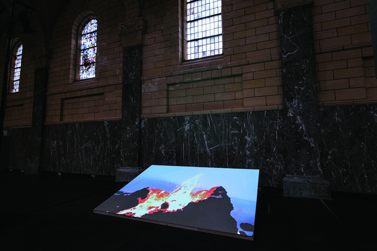 A screen with a picture on it under a stained glass arched window