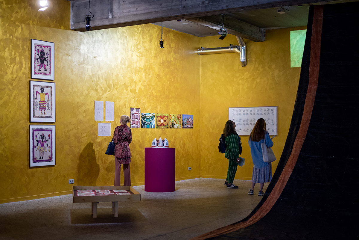 People looking at art on golden walls in a gallery