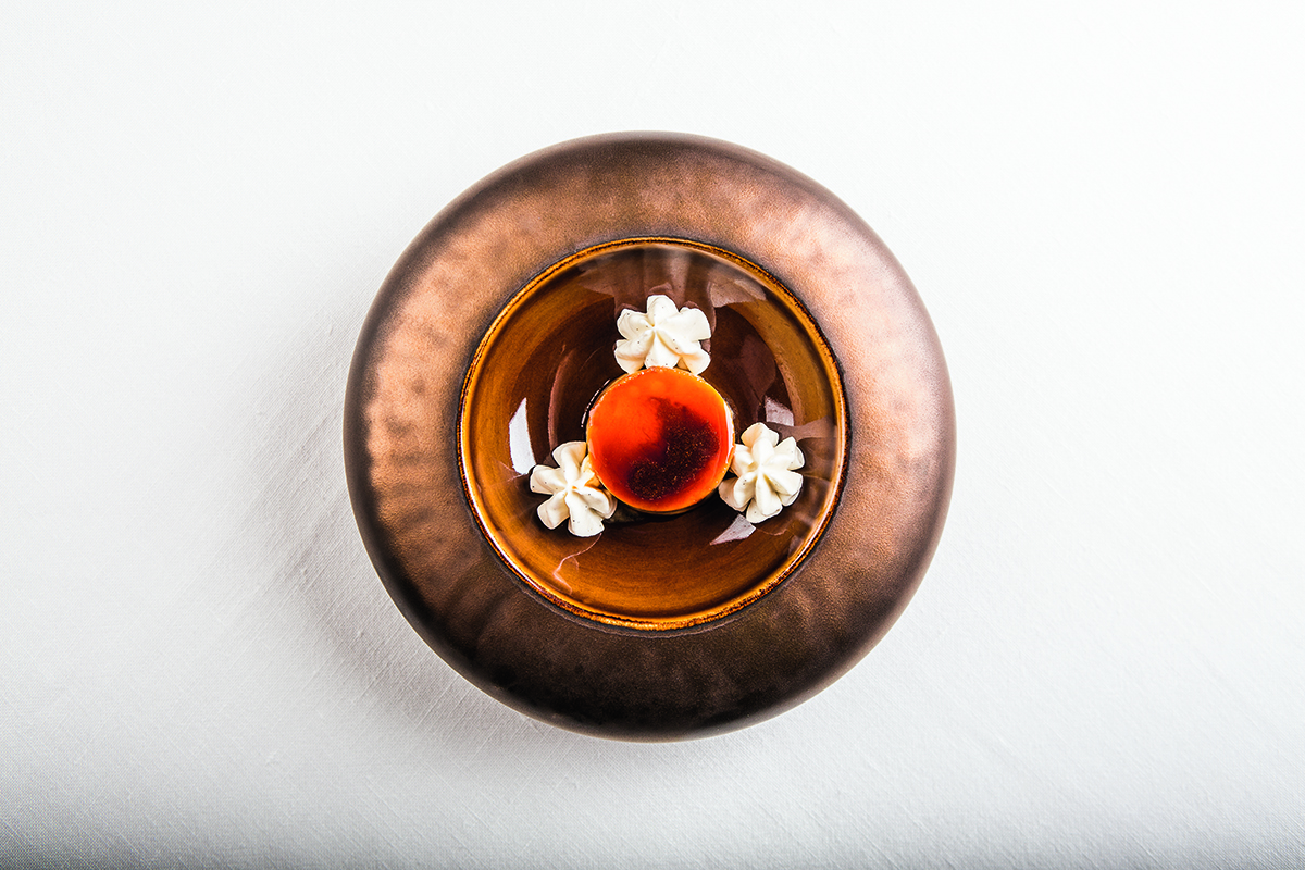 A gold plate with cream flowers and an orange ball in the centre