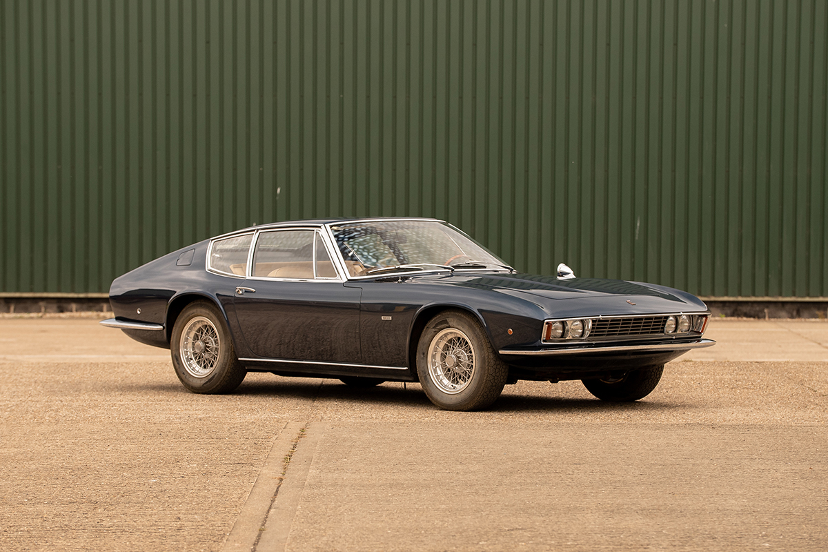 A black Monteverdi 1969 in front of a green garage