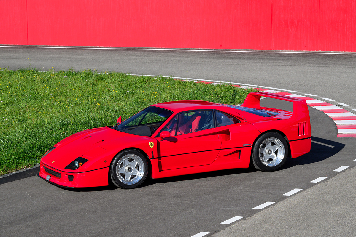 A red 1991 Ferrari F40 on a track with grass
