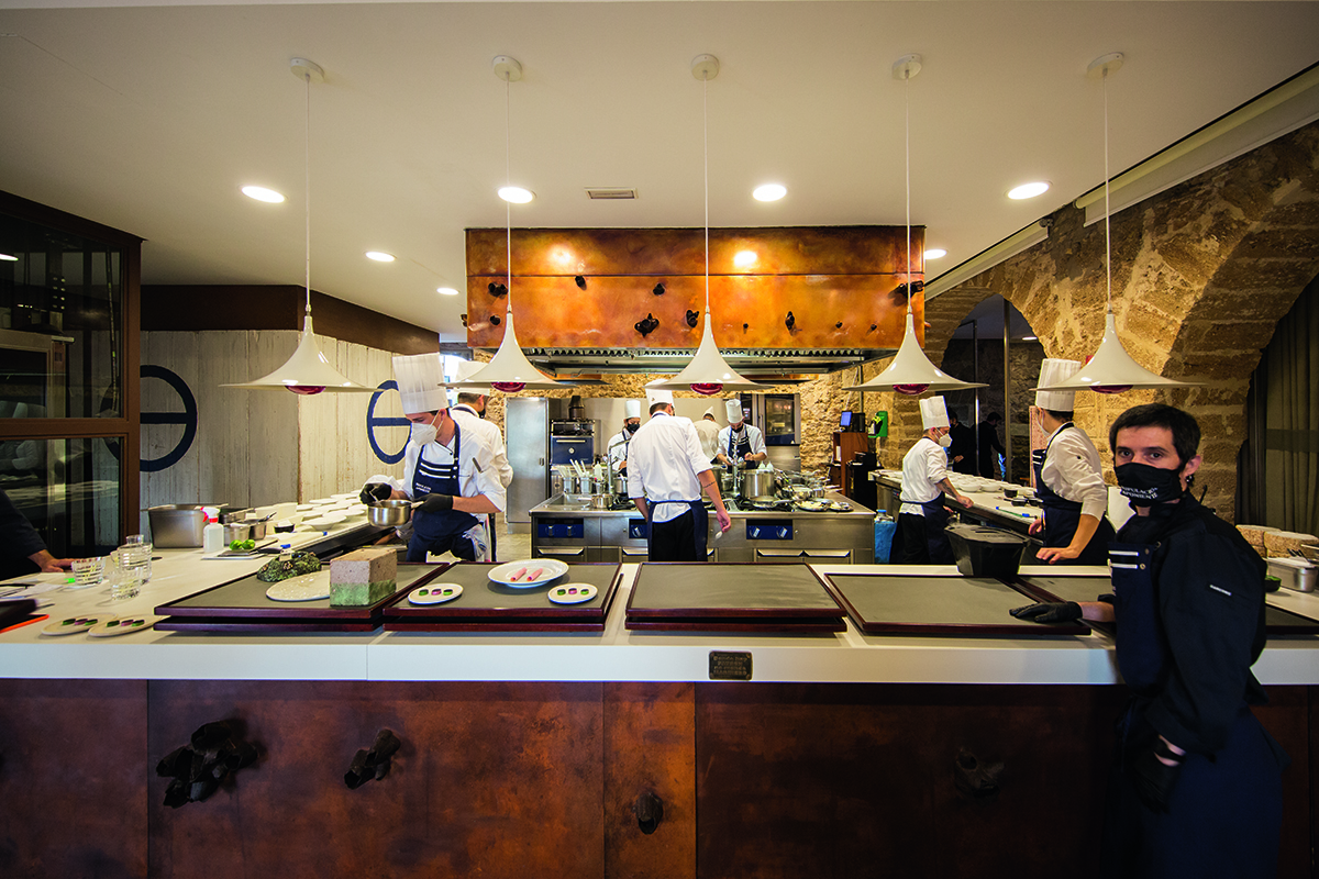 chefs working in a kitchen with dangling lights