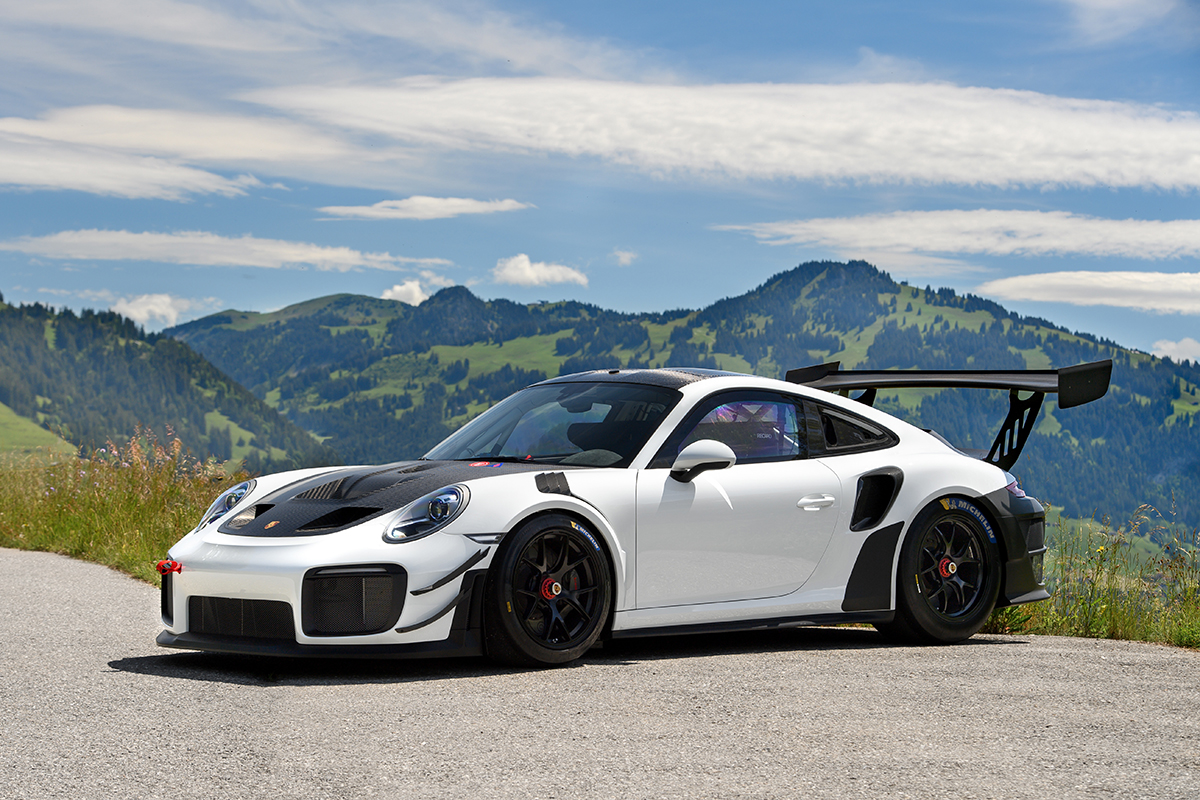 Black and white 2020 Porsche 911 GT2 RS Clubsport with green mountains and clouds in the background