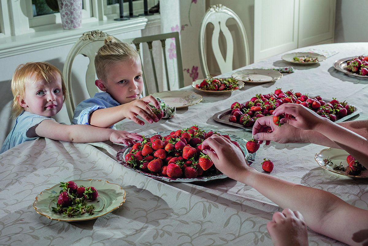 children sitting at a table eating strawberries