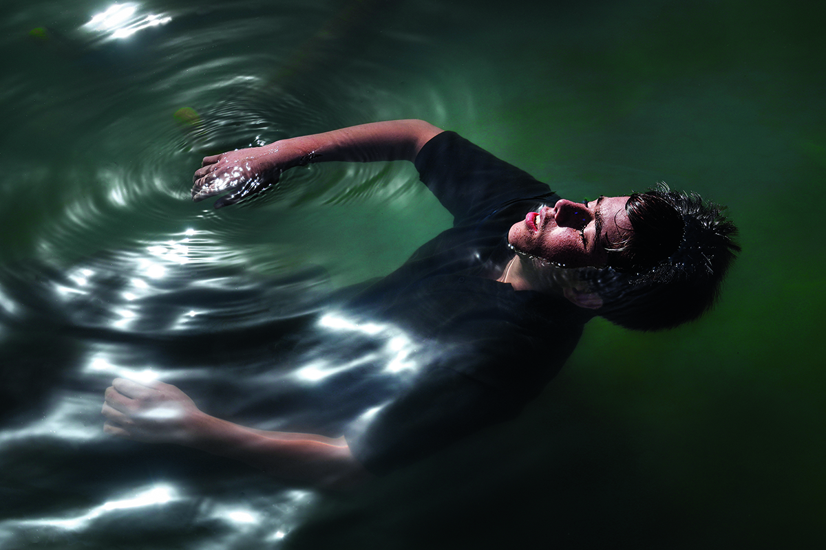 A boy wearing a black t shirt floating in water