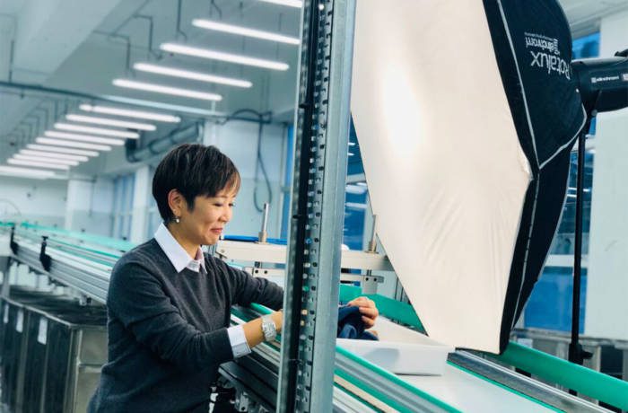 A woman in a white shirt and black jumper working in a factory