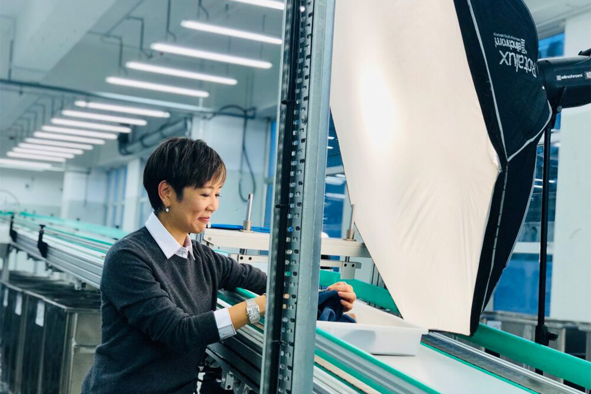 A woman in a white shirt and black jumper working in a factory