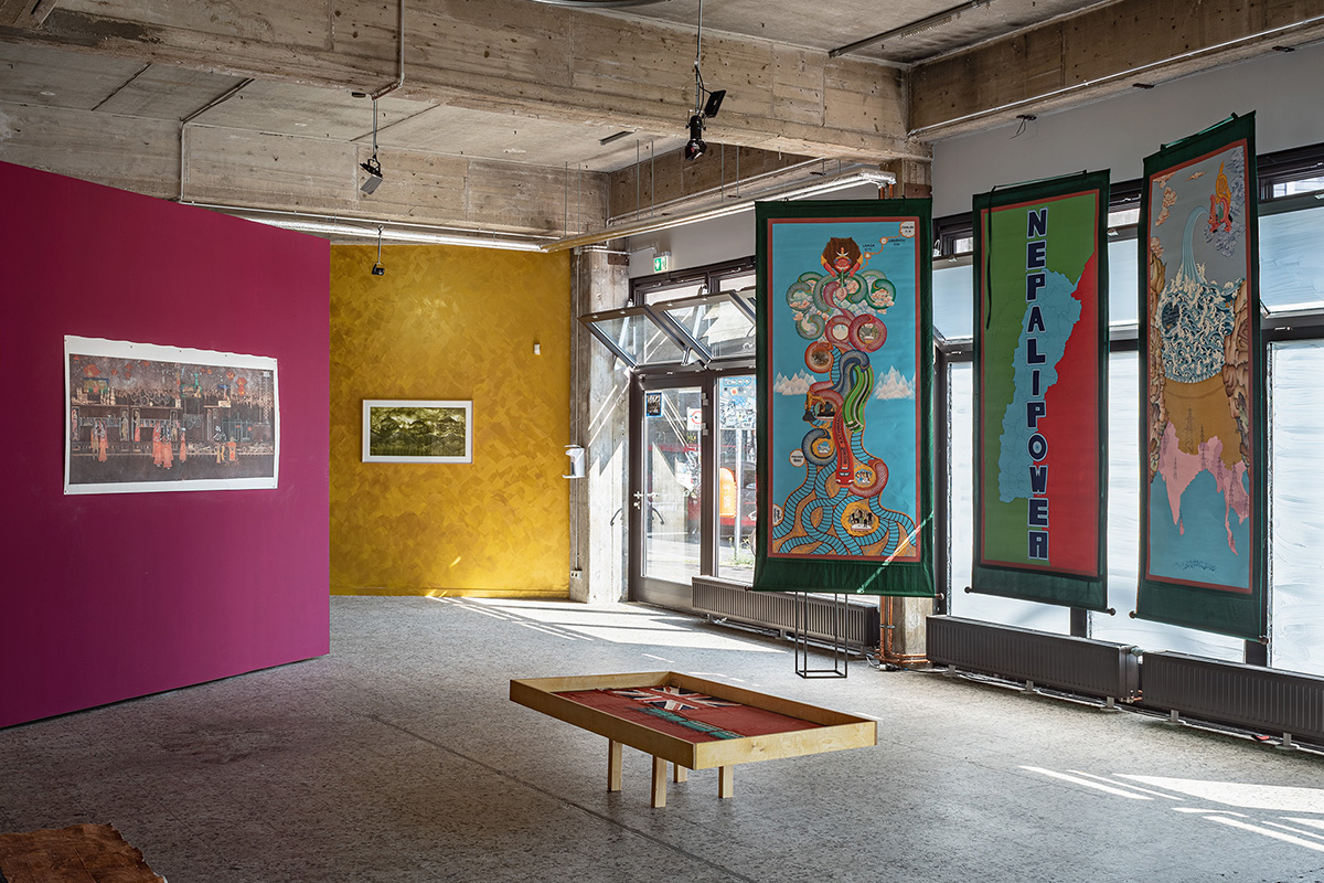 An art gallery with pink and yellow walls and a piece saying 'Nepal Power'