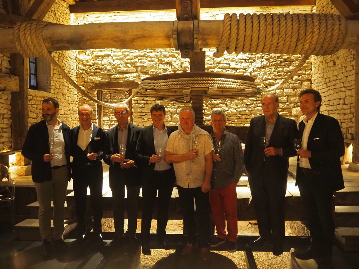 A group of men standing in a stone room holding glasses of wine