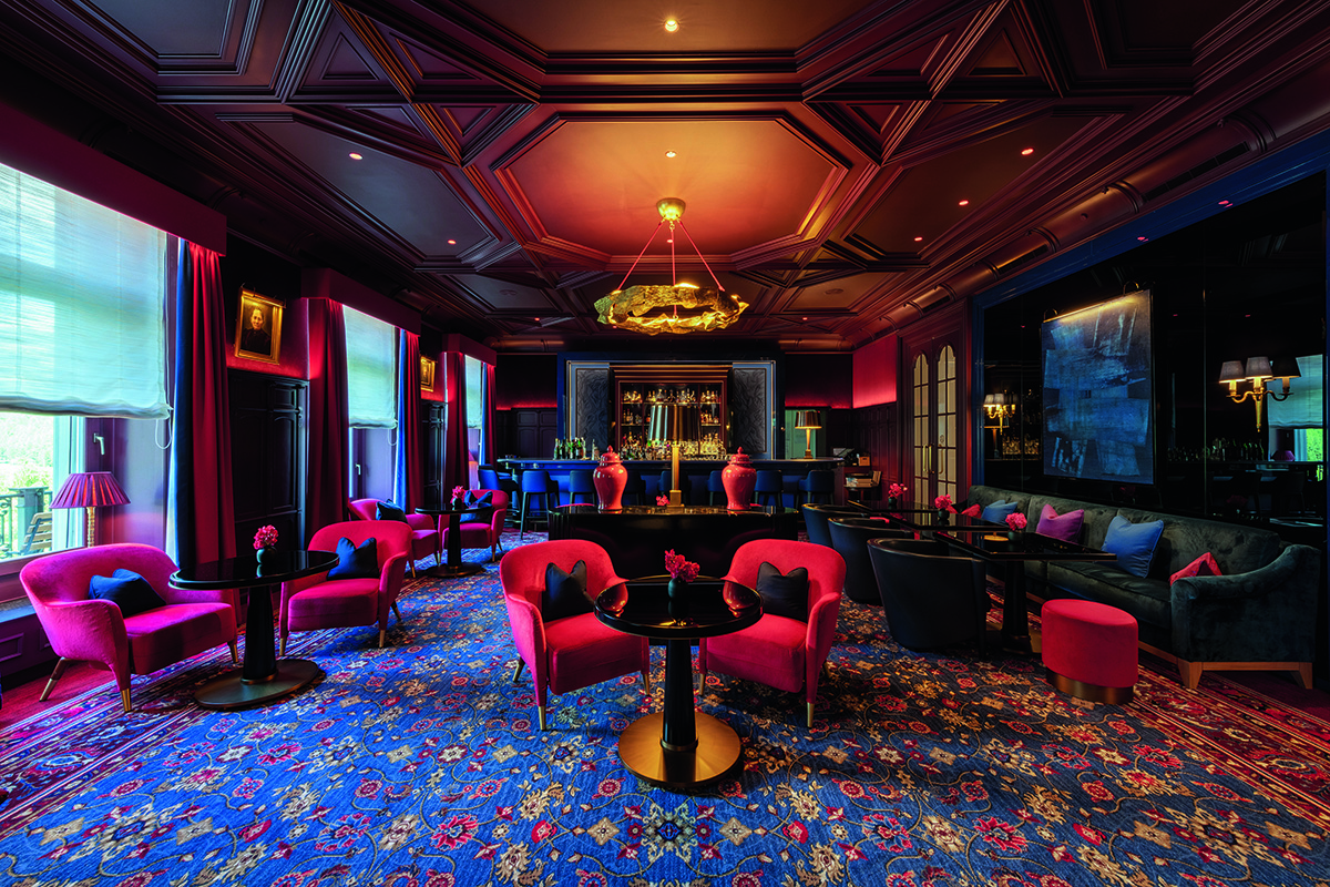 A bar with wooden walls and ceilings and red velvet chairs