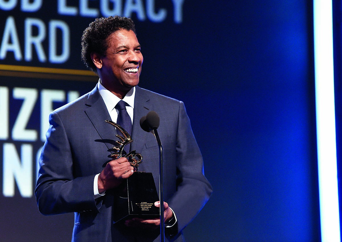 A man wearing a suit, shirt and tie holding an award