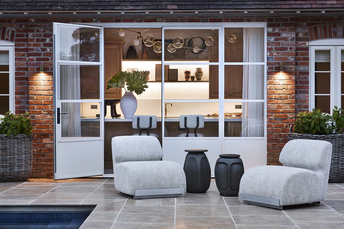 white chairs by a pool with a dining room in the background