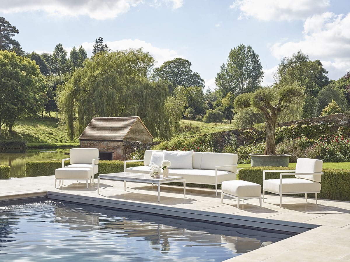 white tables and chairs in front of a swimming pool with a hut in the background