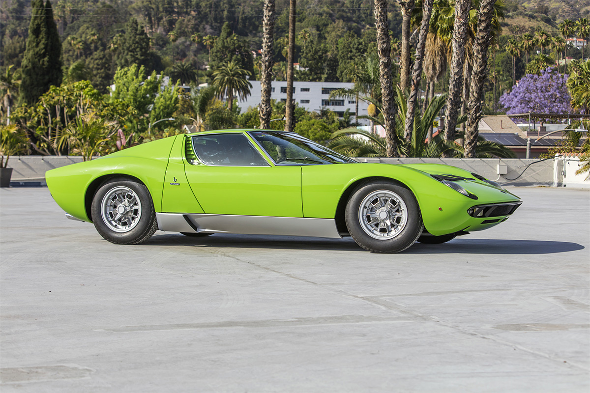 An old green Lamborghini in front of palm trees on a roof