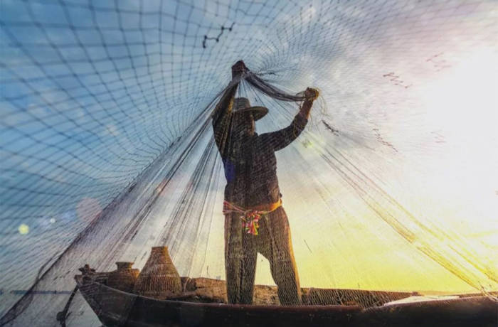 A man standing on a fishing boat holding a fishing net