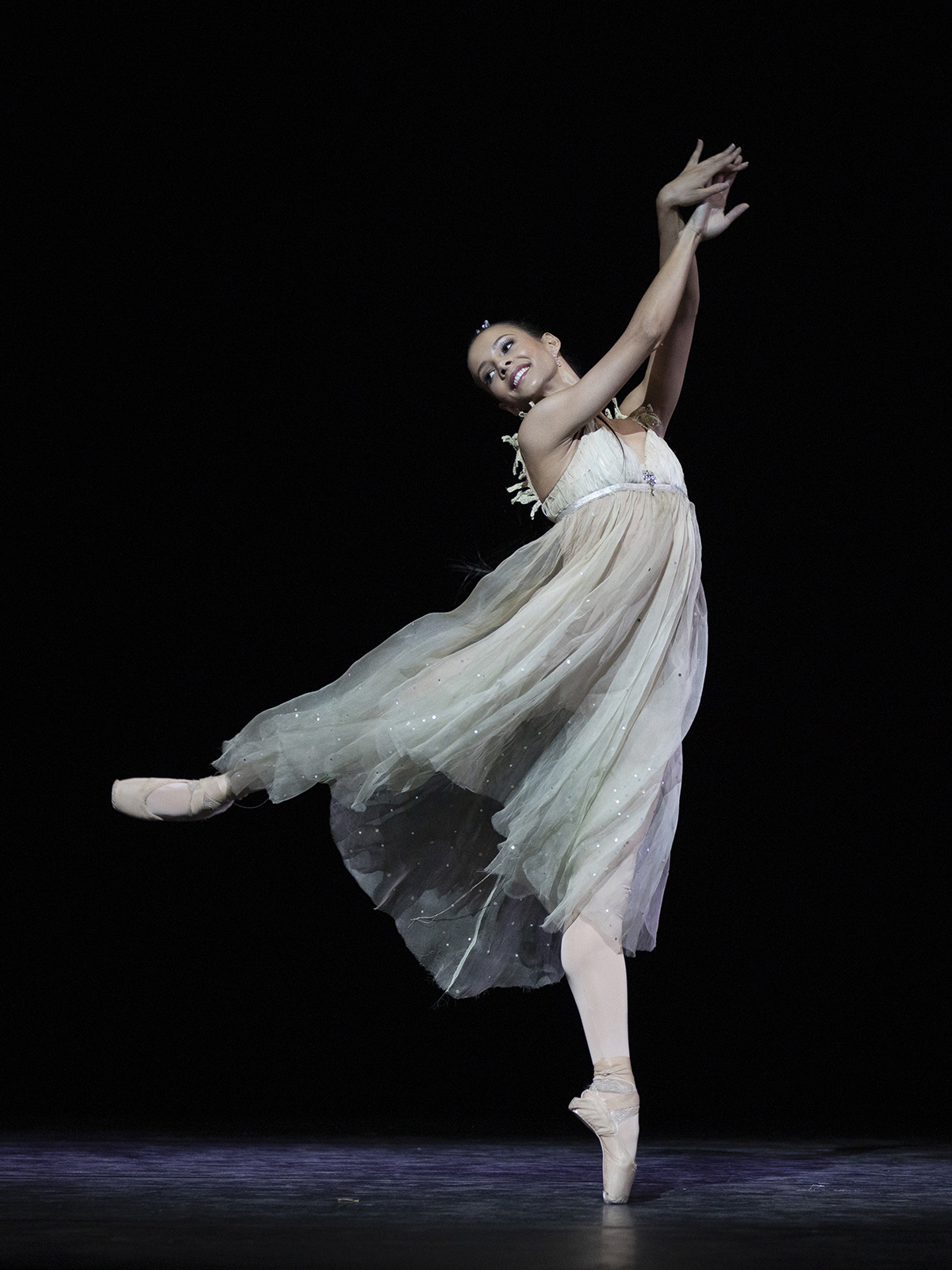 A woman dancing on a stage a flowing white dress