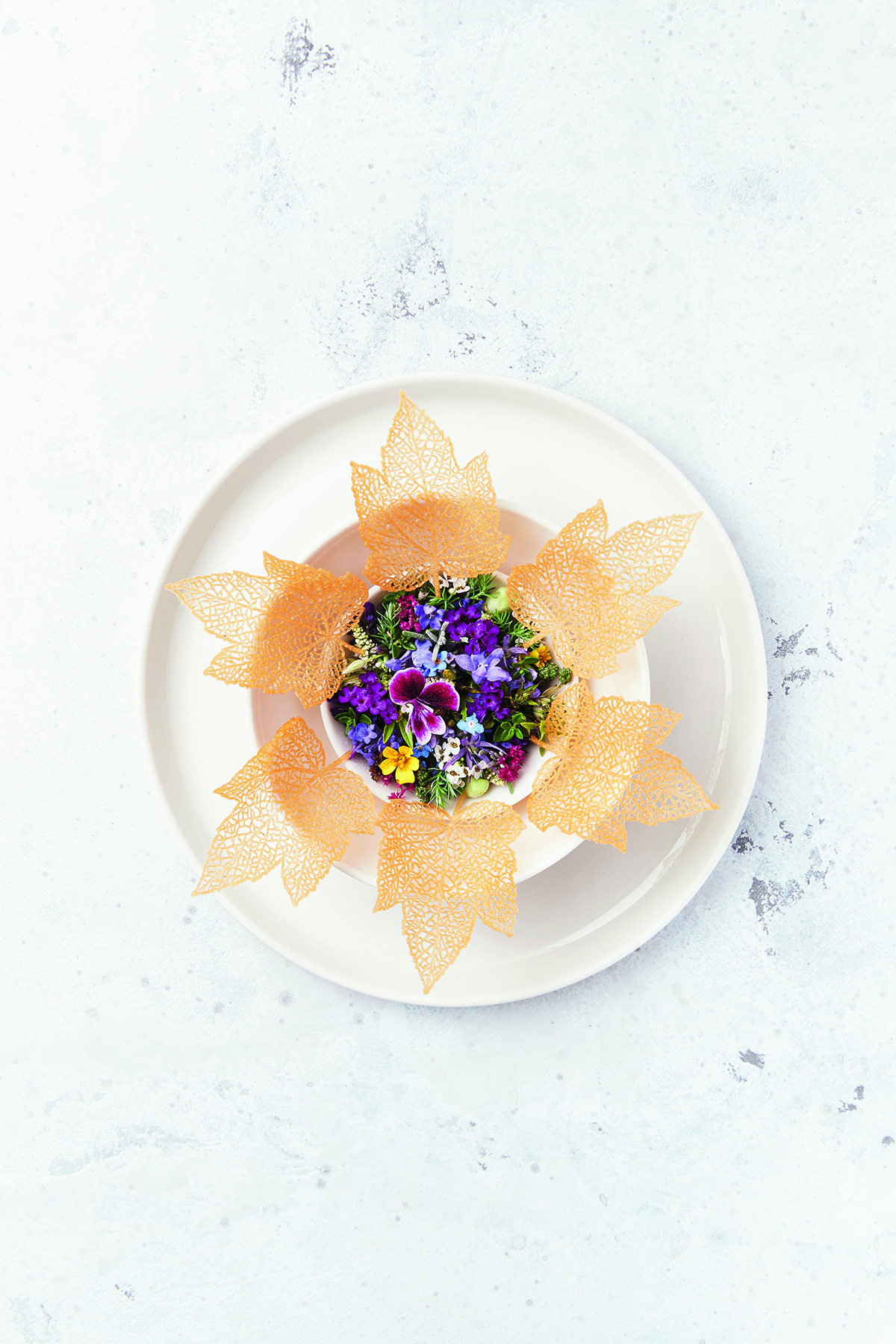 A flower shaped crust on a plate with flower petals in the centre