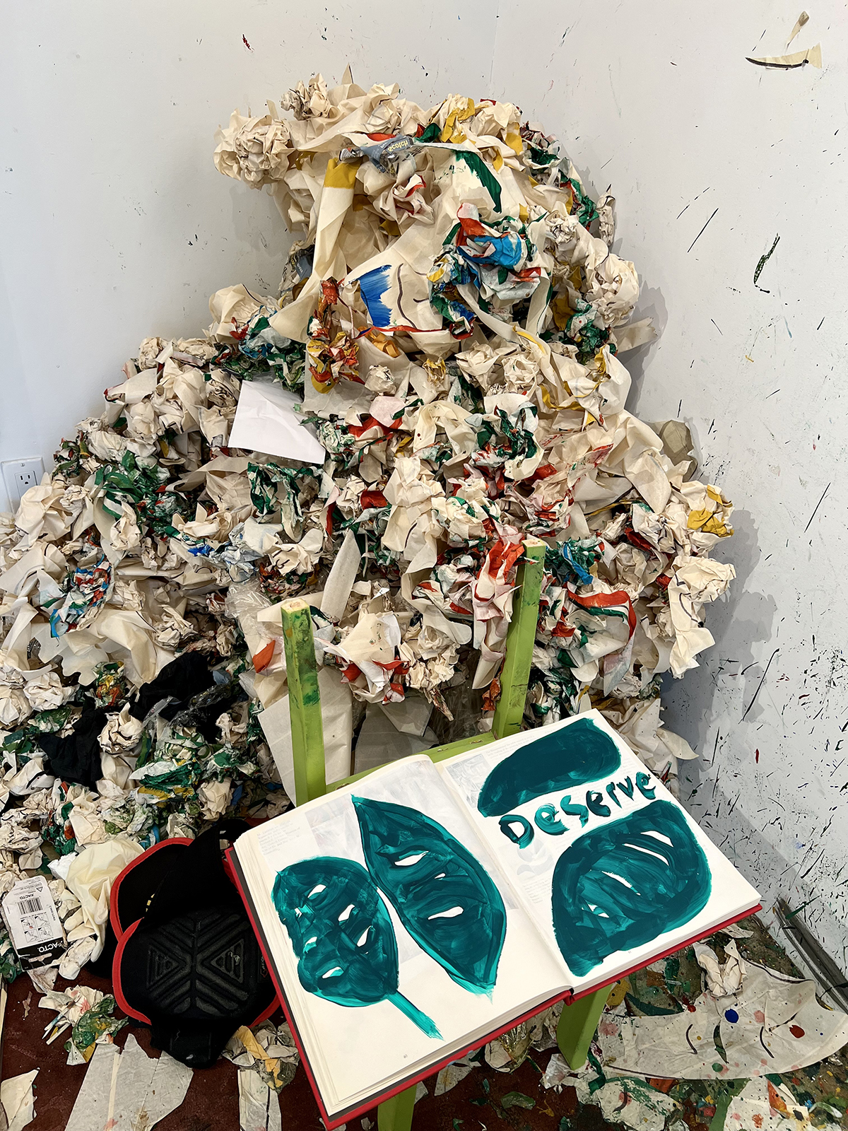 A rubbish pile in a corner of a room with a book with blue pictures in it