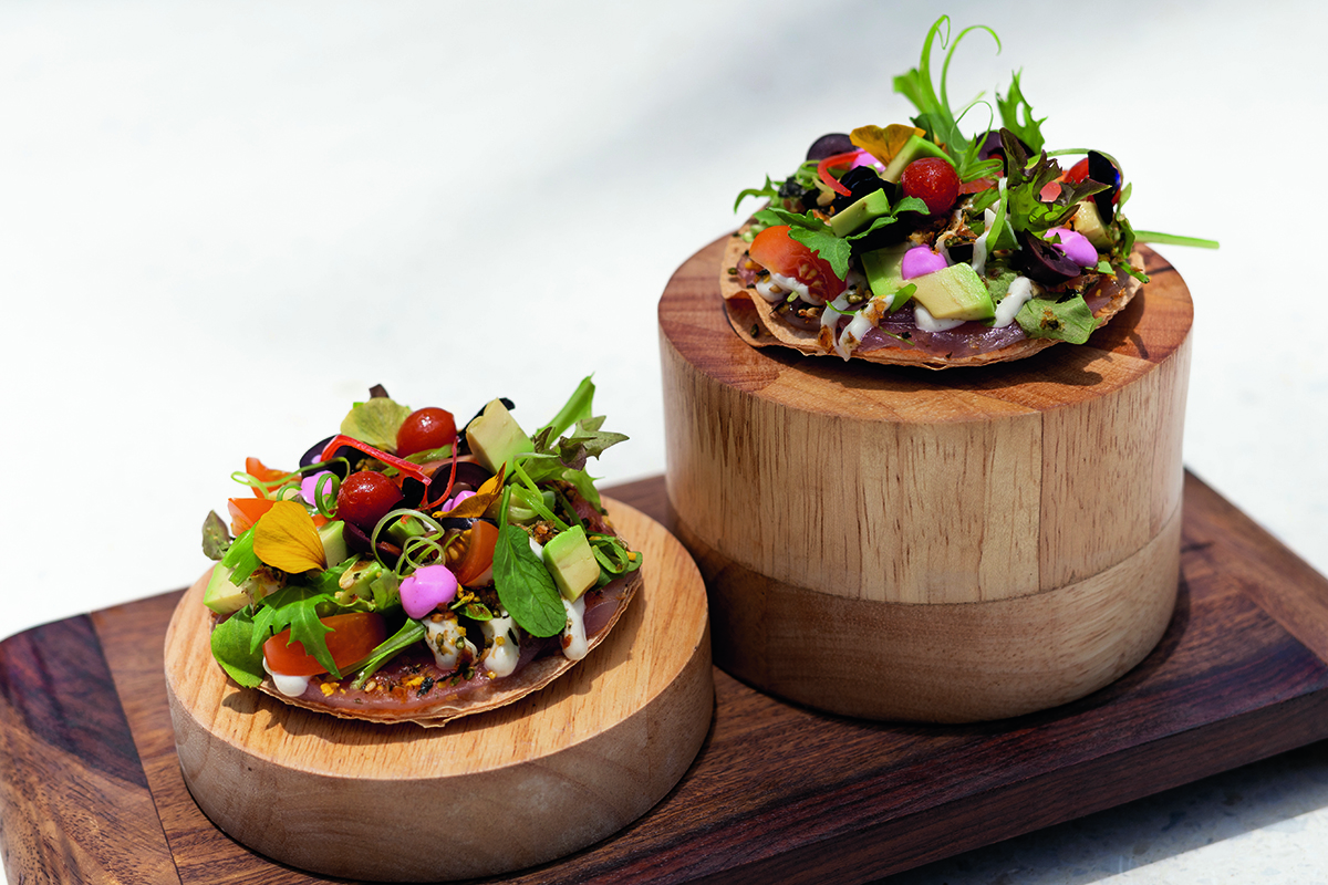 a vegetarian pizza on a wooden cylinder tray