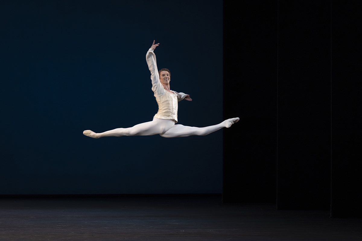 A man in a white outfit doing a ballerina jump