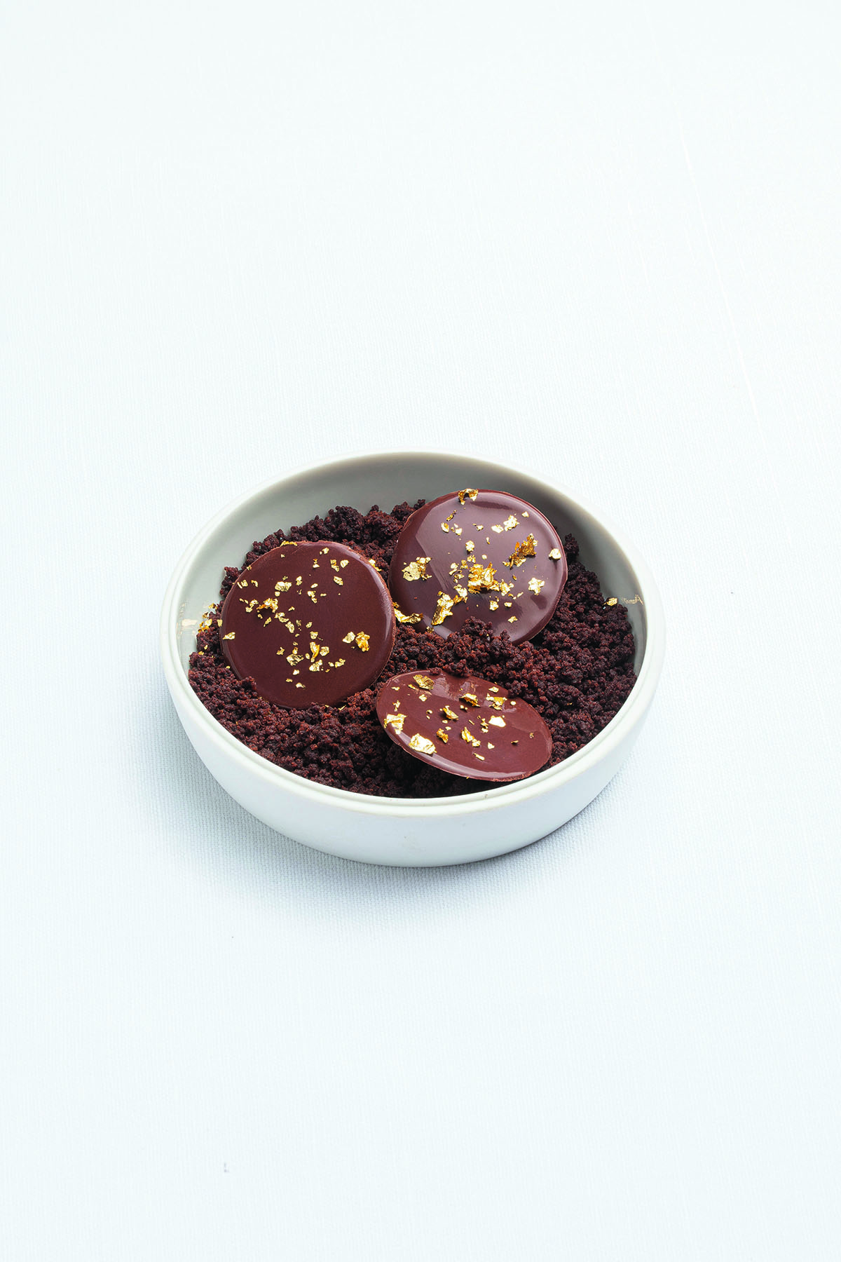 A chocolate pudding in a bowl with gold leaf on it